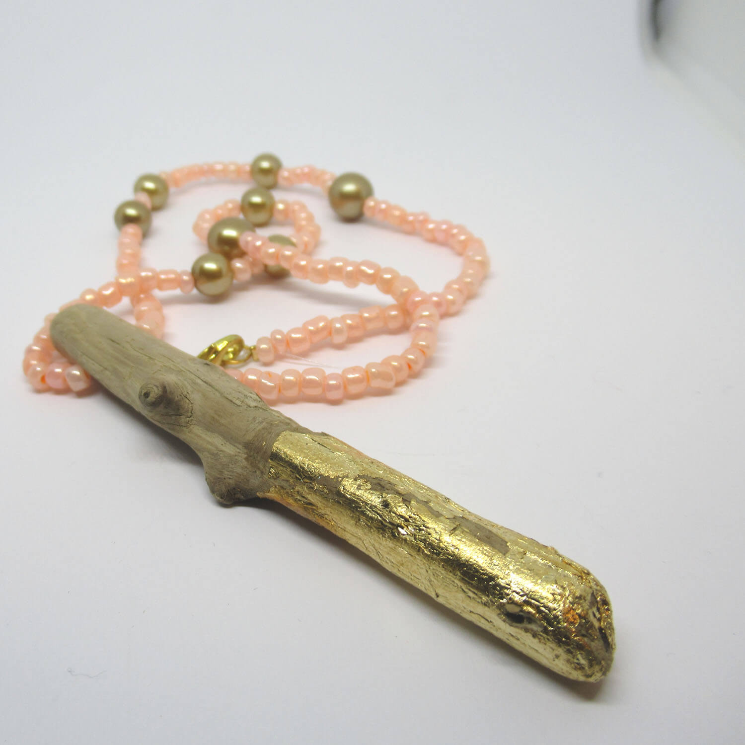 Mit Blattgold verziertes Treibholz kombiniert mit rosa und goldfarbenen Perlen